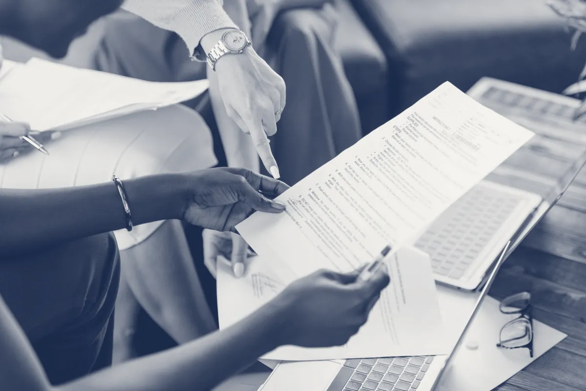 A team reviewing documents together, in JAG's navy-and-paper duotone.